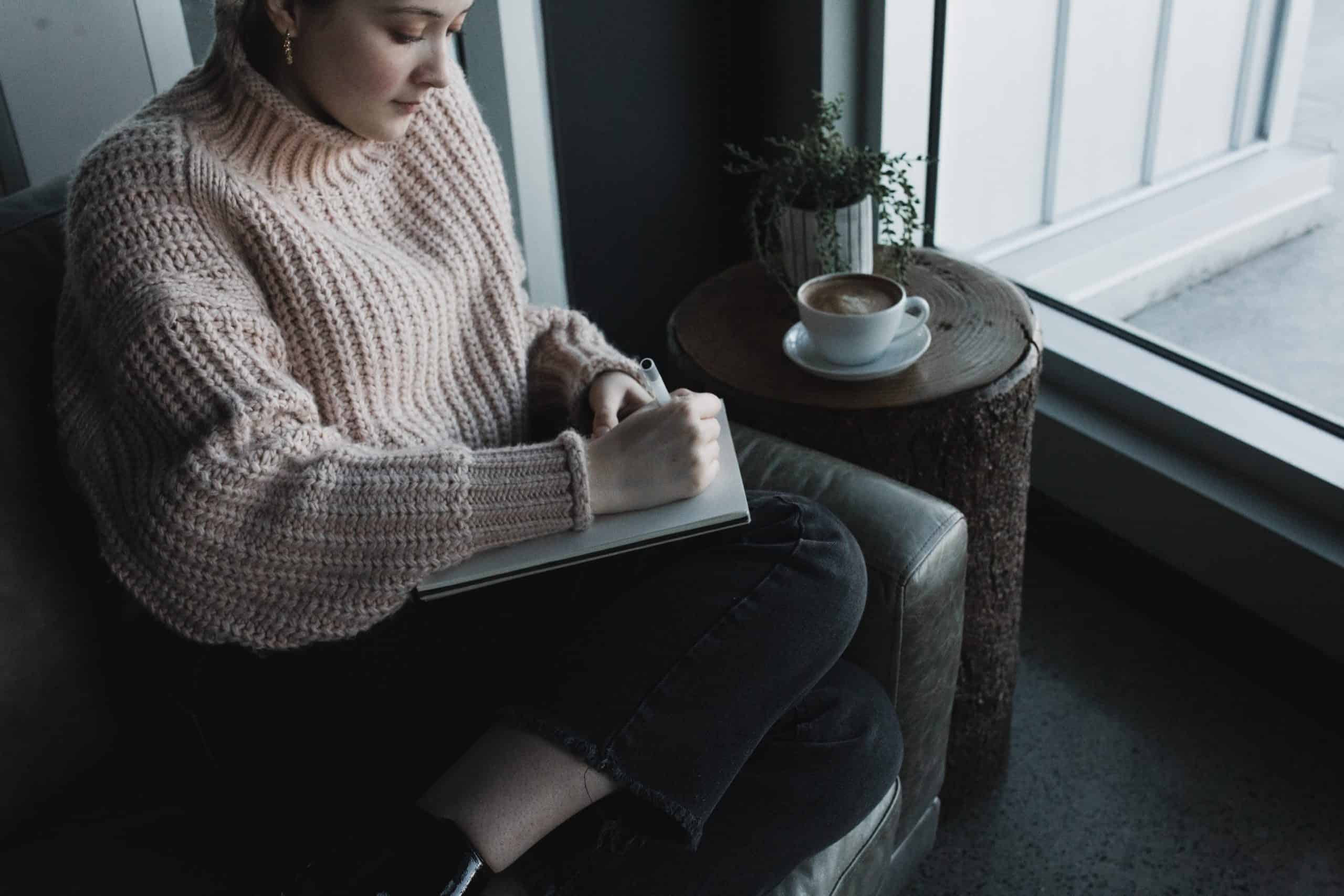 Young lady expressing herself in her journal which is an example of Self-Improvement Journal Prompts 