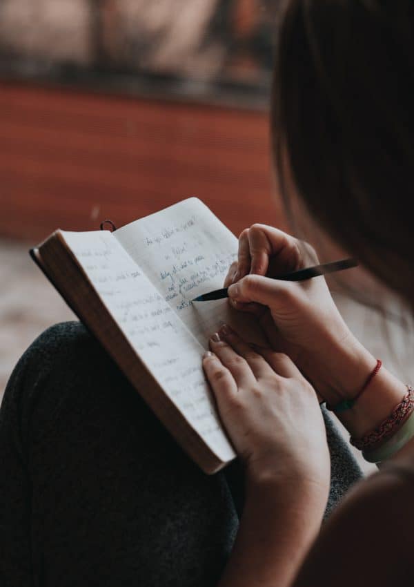 A woman writing Self-Improvement Journal Prompts 