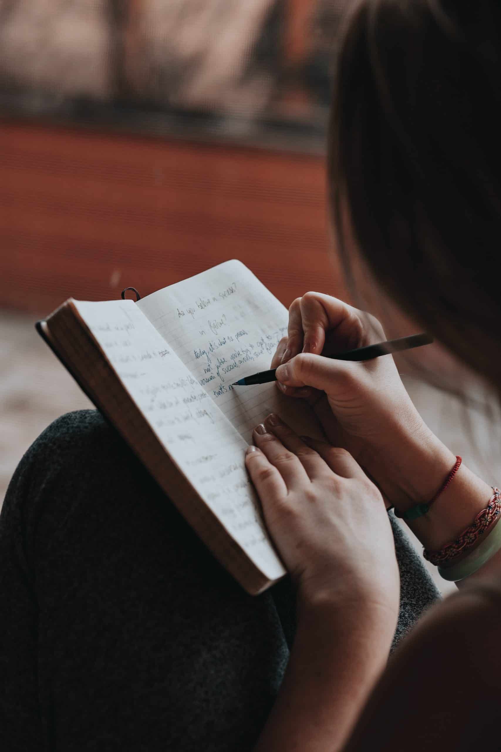 A woman writing Self-Improvement Journal Prompts 